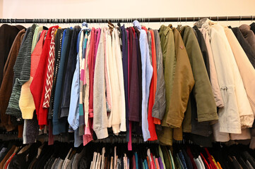 Colorful clothes hanging on a hanger for sale in shop. Clothes hanging on rack in second hand store. Pants for sale in fashion store.