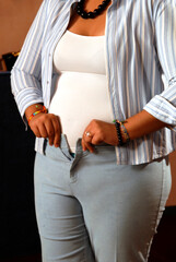 Fototapeta na wymiar overweight woman trying to button her pants, with difficulty buttoning her jeans, concept of obesity and bad habits