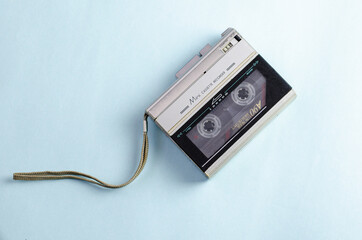 Gray cassette recorder with internal casset, isolated on blue background. 90s technology. Retro,...