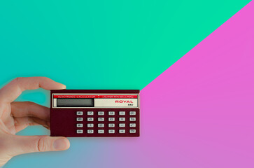 Calculator held in woman's hand. Retro, vintage, 90s technology on colorful vintage background....
