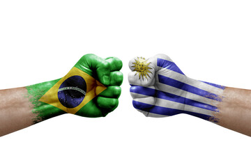 Two hands punch to each others on white background. Country flags painted fists, conflict crisis concept between brazil and uruguay
