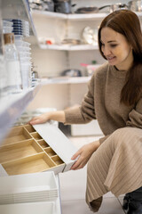 Modern woman choosing eco friendly wooden container for things neatly placing Marie Kondo storage