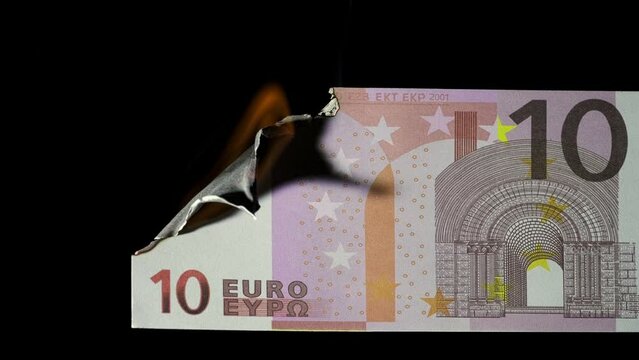 Close up footage of a 10 euro banknote burning on a black background.