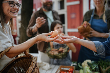 Close up of woman buying organic eggs outdoors at local farmers market.