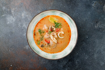 Tom Yam soup with chicken on dark stone table top view