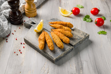 fried surmullet on board with lemon on grey wooden table