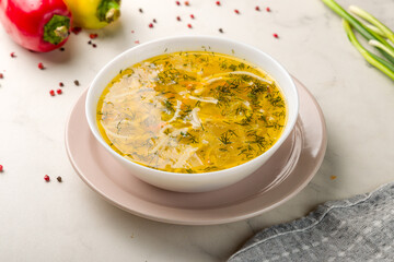 Chicken soup bouillon in a plate on white marble table