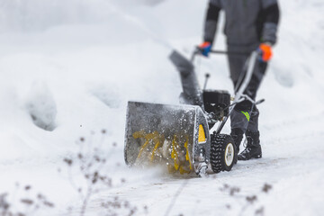 Process of removing snow with portable blower machine, worker dressed in overall workwear with gas...