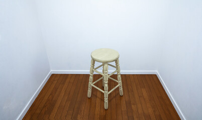 White room with a white round stool in the middle.