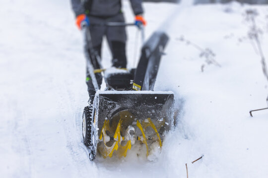 Process of removing snow with portable blower machine, worker dressed in overall workwear with gas snow blower removal on the street during winter