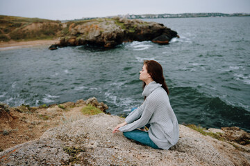 Naklejka na ściany i meble woman seated on the coast sweater landscape female relaxing