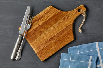 Brown wooden cutting board with cutlery and dinner napkins
