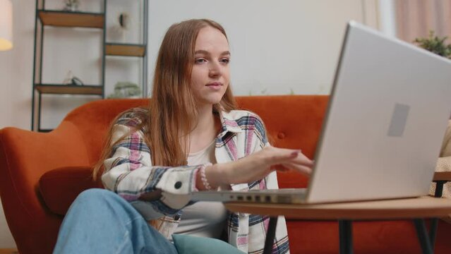 Young woman using laptop computer sitting on floor working from home office. Adult girl elearning, browsing internet, doing online shopping, remote job ordering food delivery on pc tech in living room