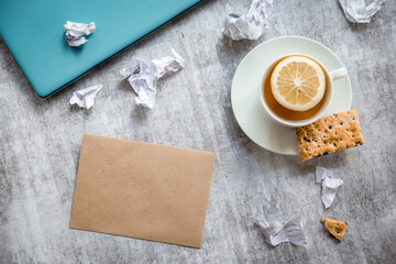 letter envelope with blank white paper for a message on plain grey background, and cup of tea, freelance work.