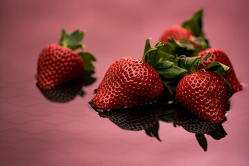 Fresh strawberries on a red background with reflection