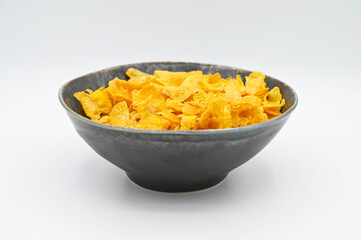 Corn Flakes, in a dark grey bowl, isolated on a white background