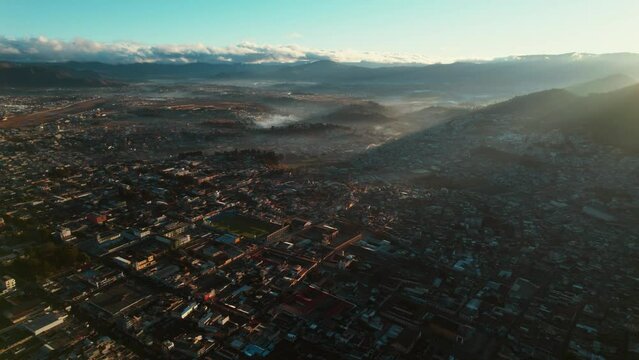 Xela Quetzaltenango Guatemala. Drone Aerial Flying Down Over Guatemalan Colonial City During Dramatic Hazy Sunrise Dawn.