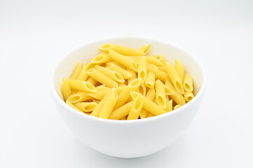 Raw penne rigate pasta, in a white bowl, isolated on a white background
