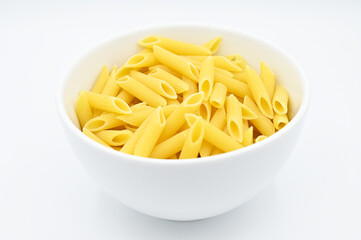 Raw penne rigate pasta, in a white bowl, isolated on a white background
