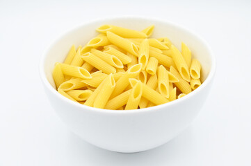 Raw penne rigate pasta, in a white bowl, isolated on a white background
