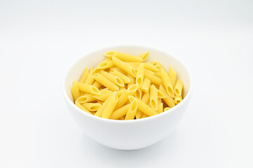 Raw penne rigate pasta, in a white bowl, isolated on a white background
