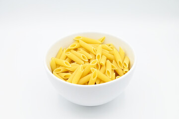 Raw penne rigate pasta, in a white bowl, isolated on a white background
