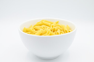 Raw penne rigate pasta, in a white bowl, isolated on a white background
