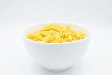 Raw penne rigate pasta, in a white bowl, isolated on a white background
