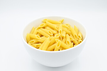 Raw penne rigate pasta, in a white bowl, isolated on a white background