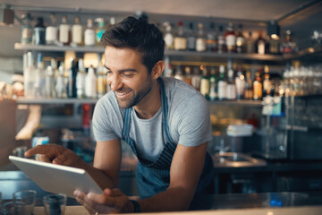 Streamlining small business tasks with smart tech. Shot of a young man using a digital tablet while...
