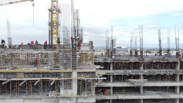 Vuelo a&eacute;reo con giro 180 grados captando obreros trabajando proyecto inmobiliarios, con fondo de la cuidad urbana de santo domingo 