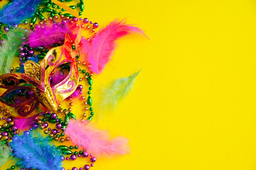 Carnival mask with feathers on yellow background. Multicolored beads Mardi Gras or Fat Tuesday symbol.