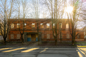 Fototapeta na wymiar old abandoned red brick building in the rays of the bright afternoon sun on a clear spring day 
