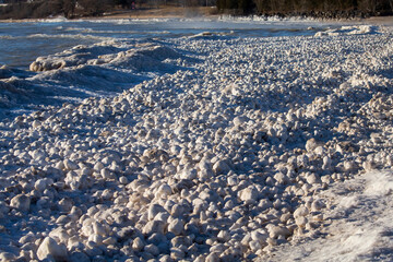 Snow, frost, and wind create irregularly shaped ice balls on the shores of Lake Michigan