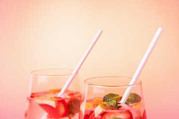 Two glasses with iced tea with pieces of strawberry and grapefruit, front view.