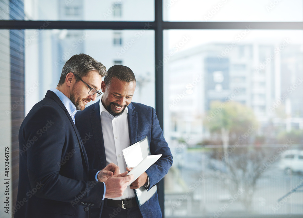 Poster improving professional performance with the latest apps. shot of two businessmen using a digital tab