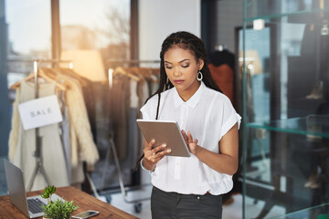 My tablet makes it easier to connect with my clientele. Cropped shot of a young business owner using her tablet while standing in her store.