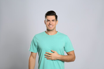 Happy healthy man touching his belly on light grey background