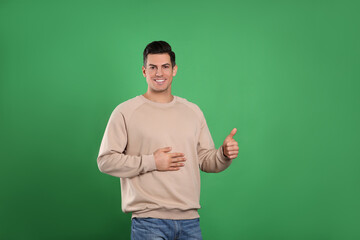 Happy healthy man touching his belly on green background