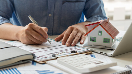 Fototapeta premium People calculate interest, taxes, and profits to invest in real estate and home purchases. Real estate agents with home layouts are talking to clients about purchasing home insurance.