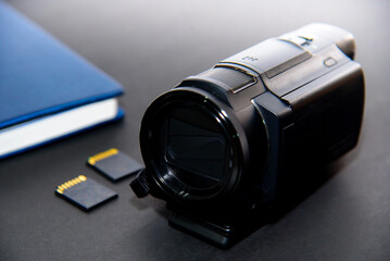 4K video camera with notebook and memory card on black