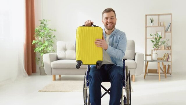 Happy disabled person in a wheelchair with a yellow suitcase in his hands is preparing for a trip