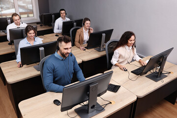 Call center operators with headsets working in modern office, above view