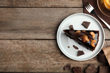 Piece of tasty homemade chocolate cake with nuts on wooden table, flat lay. Space for text