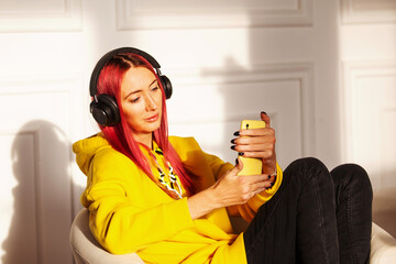 adult girl with headphones and phone with red bright hair