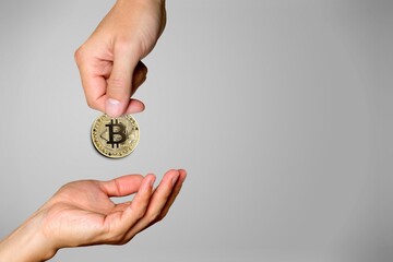 Businessman giving golden bitcoin to another human. two hands exchanging cryptocurrency.