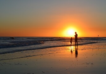 A father and a daughter enjoy the sunset on the beach, next to the sea of ​​the Argentine coast