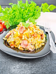 Cabbage stew with sausages in black plate on dark board
