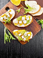 Bruschetta with pumpkin and arugula on dark board top
