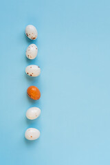 Easter minimal composition with multicolored eggs on the blue background. Easter concept. Copy space, flat lay. Vertical photo.